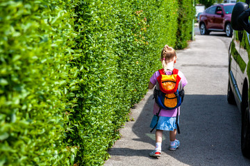 Little girls walking away with her filled backpack