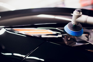 Car polish wax worker hands holding polisher and polish car detailing or valeting concept front...