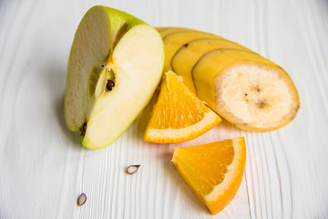 Sliced apple, orange and banana on white