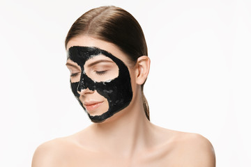 Young beautiful woman applying a mask for the face of the therapeutic black mud. Spa treatment