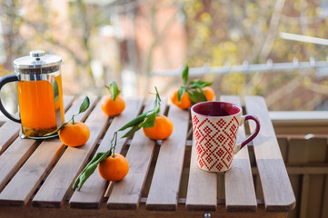 Glass teapot, mug and tangerines on wooden table