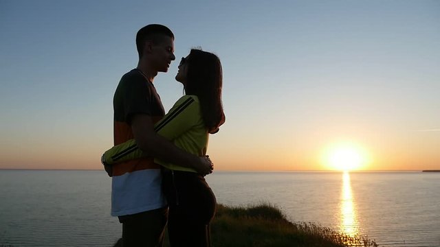 A romantic view of apassionate pair embracing each other and looking at each other at a splendid sunset on the Black sea coast in summer