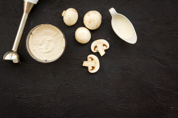 Fototapeta na wymiar Cook cream soup with mushrooms. Champignon and blender on black background top view copy space