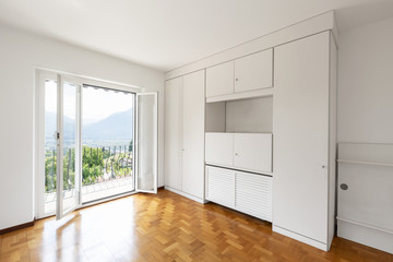 Empty white room with parquet and large windows