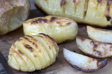Baked potatoes of different kinds located on a wooden background in rustic style close-up