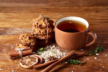 Christmas teatime with oatmeal, chocolate biscuits, and spices, on wooden background, close-up, selective focus.