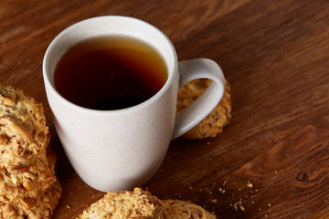 White porcelain mug of tea and sweet cookies on wooden background, top view, selective focus