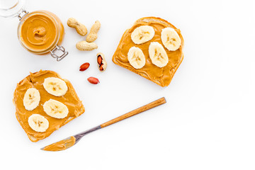 Sandwich with nut butter and banana for breakfast on white background top view copy space