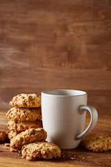 White porcelain mug of tea and sweet cookies on wooden background, top view, selective focus