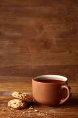 Porcelain cup of tea and sweet cookies on wooden background, top view, selective focus