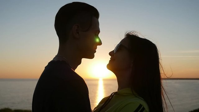 Profile of an amorous pair hugging each other and enjoying life at sunset on the Black Sea shore in summer. The sun path is right between them