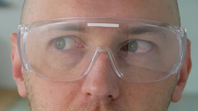 vision, eyewear and people concept - close up of male face in safety glasses or goggles