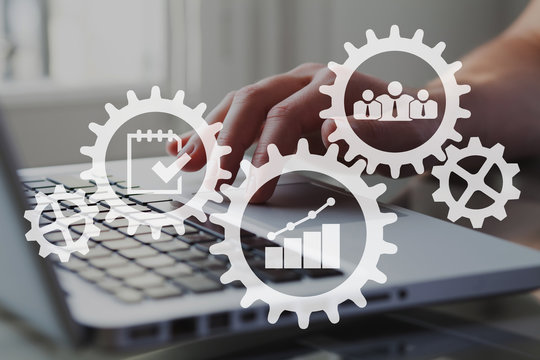 Icons of gears, cogwheels and charts with businessman working on computer on background. Teamwork and corporate business concept.