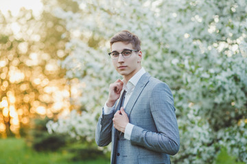 Fototapeta premium stylish groom in glasses posing in a suit at sunset