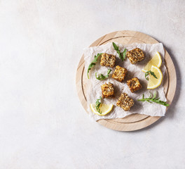 Cheese, diced and fried in batter and sesame on a wooden Board. White background. Top view.
