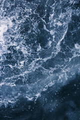 Fototapeta na wymiar The surface of the sea with waves, splash, foam and bubbles at high tide, blue abstract background