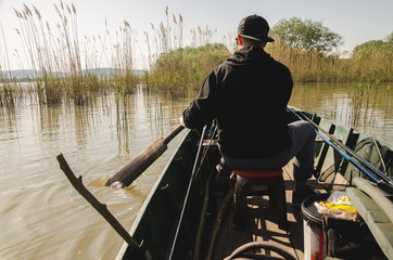 Young man rowing a boat while looking for place to fish