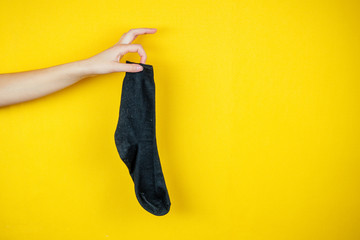 old smelly holey sock in hand on a yellow background - obrazy, fototapety, plakaty