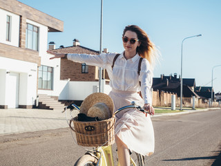 Plakat Pretty girl in hat and dress by cruiser bicycle in suburb