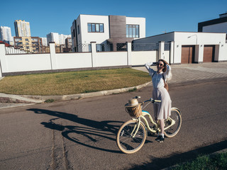Plakat Pretty girl in hat and dress by cruiser bicycle in suburb