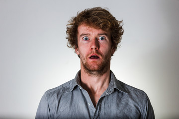 Surprised young man on grey background