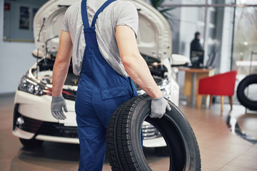 Fototapeta na wymiar Mechanic holding a tire tire at the repair garage. replacement of winter and summer tires