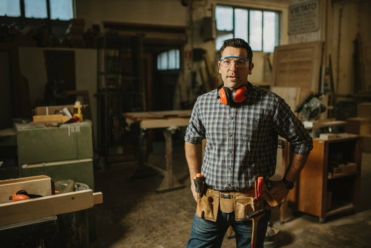 A mature carpenter standing confidently in his workshop