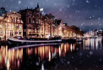 Fototapeta na wymiar Beautiful night in Amsterdam. Night illumination of buildings and boats near the water in the canal during a snowstorm. Bokeh light effect, soft filter