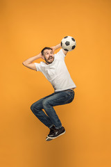The young man as soccer football player kicking the ball at studio