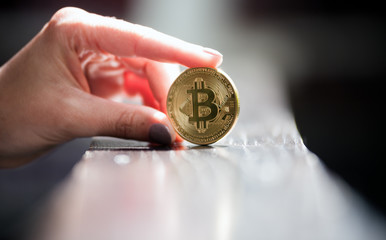 Female hand holding golden bitcoin coin, symbol of crypto currency