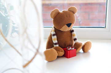 Toy teddy bear and wedding rings on a red jewelry box.