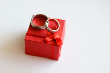 Wedding rings on a red jewelry box on a white background.