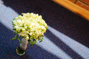 A wedding bouquet of white freesias with a decorative butterfly.