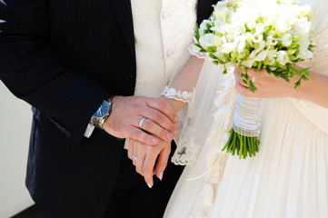 The bride and groom hold hands during the walking in the park. Wedding day in summer.