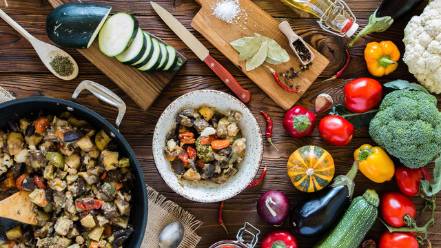 vegetable stew in the  pan and plate and fresh vegetables ingredients on wooden table,  top view