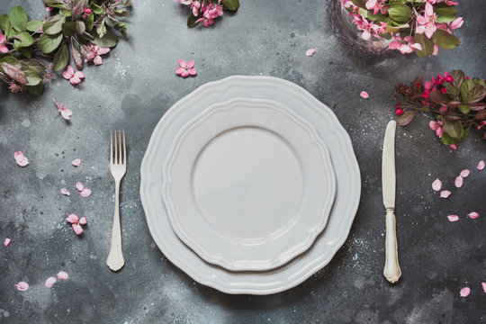 Spring table place setting with romance pink flowers, silverware on vintage background. View from above.