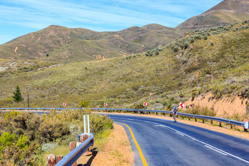A cyclist cycles on the R46 road from Ceres over the mountains into the Karoo desert. Ceres, South Africa.