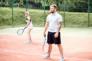 Young couple in white sports wear playing tennis on the tennis court outdoors