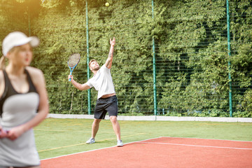 Young couple in white sports wear playing tennis on the tennis court outdoors