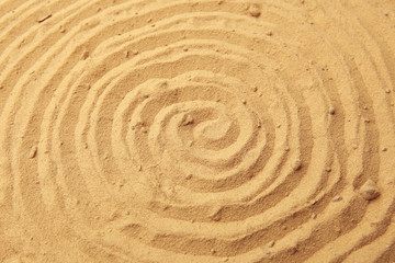 Fototapeta na wymiar Spiral drawing on beach sand background. Spiral pattern on golden sand. Sand texture.