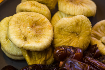 dried dates and figs in a ceramic plate on a wooden table