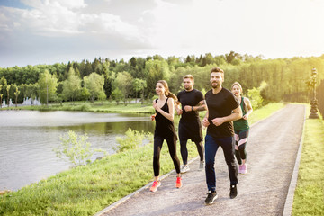 Group of friends jogging during the morning exercise in the park near the lake
