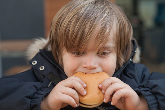 Little boy (5-6) eating hamburger