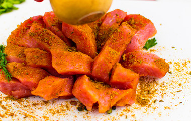 Fillet of pork chopped slices sprinkled with spices on a white background.