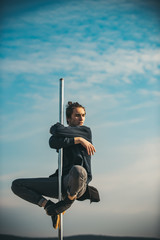 Athletic guy make acrobatic elements on pylon. athletic man sit on pole.