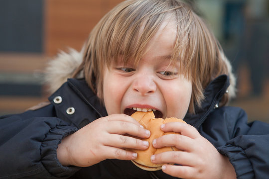 Little boy (5-6) eating hamburger