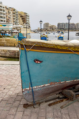 Fototapeta na wymiar Traditional Maltese fishing boat on a boat ramp at Spinola Bay, St. Julian's, Malta