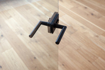 Fototapeta premium Glass door with metallic handle open in to the empty room with wooden floor