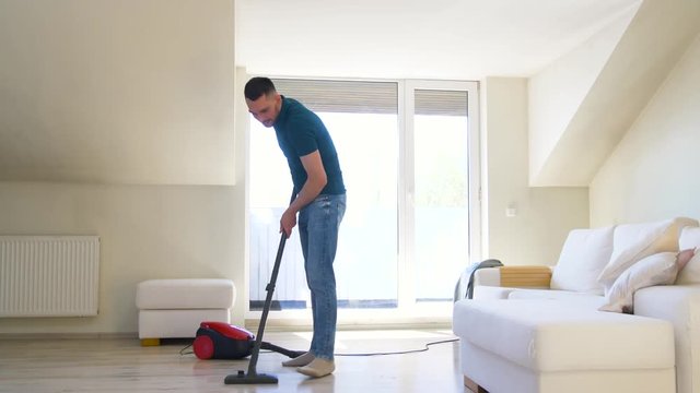 household and cleaning concept - man with vacuum cleaner at home