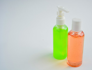 Two transparent plastic bottles with liquid soap on a light background